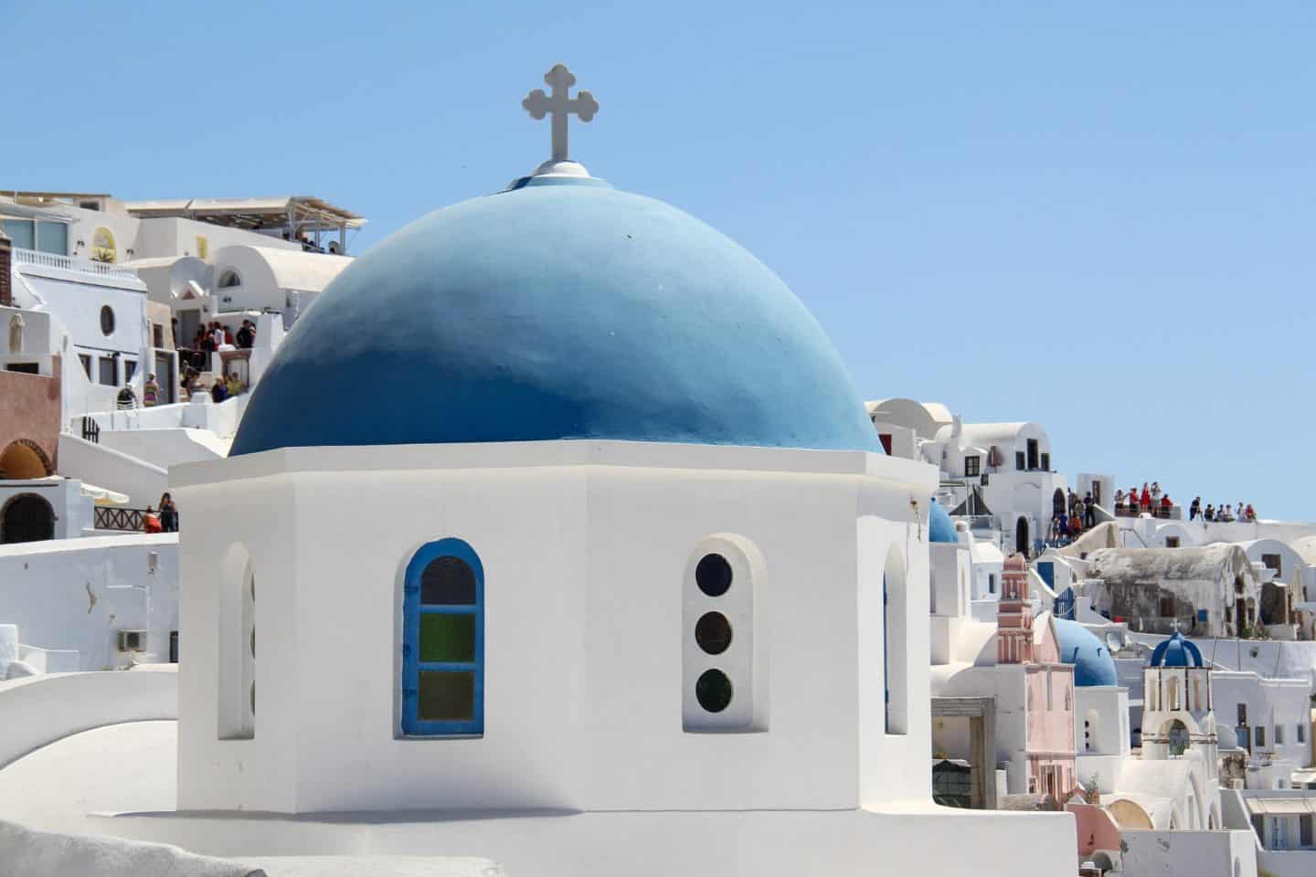 white church building with blue roof in oia greece 