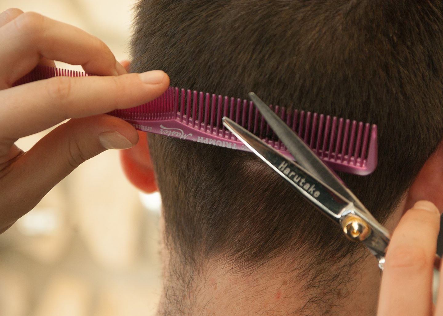 hairdresser cutting mens hair with comb and scissors