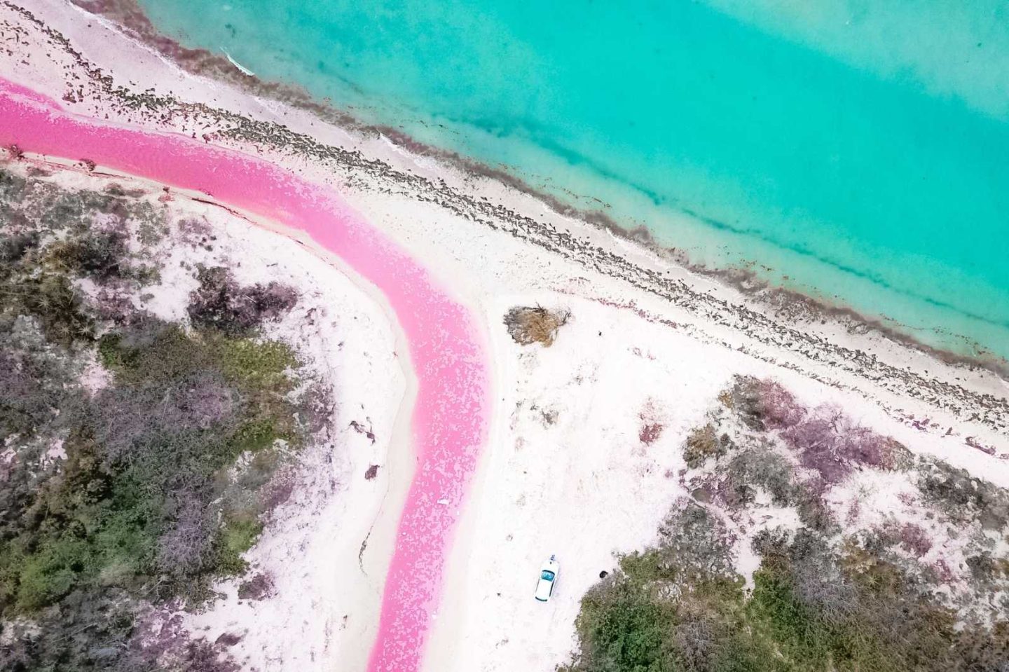 aerial view of rive flowing pink water at pink lakes of los coloradas
