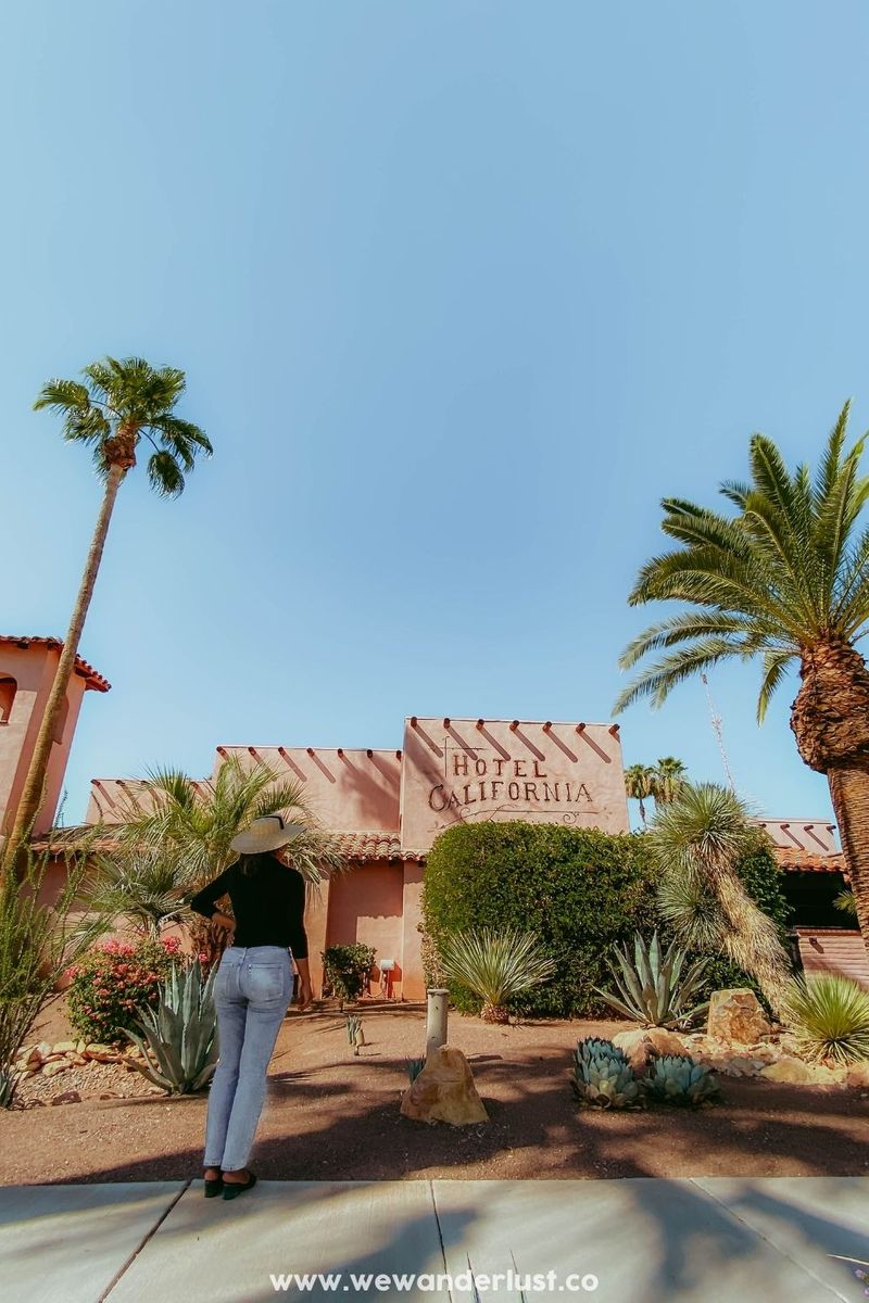 woman standing in front of hotel california in palm springs wewanderlustco