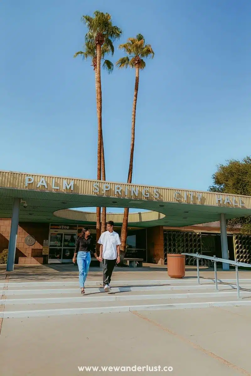 couple holding hands in front of palm springs city hall www.wewanderlust.co